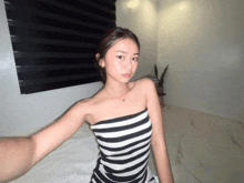 a woman in a black and white striped strapless top takes a selfie