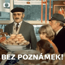 a man in a suit stands in front of a display of donuts with the words bez poznamek written below him