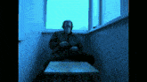 a man sits at a table in front of a window