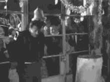 a black and white photo of a group of people standing in front of a store window .