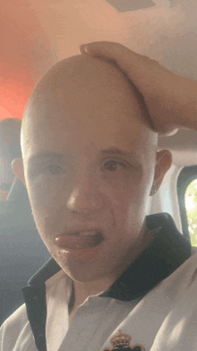 a man with a bald head is wearing a white shirt with a crown on it