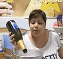 a woman is holding a bottle of champagne and pouring it into a bowl .