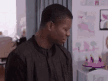 a man in a black shirt is standing in a room in front of a wall .