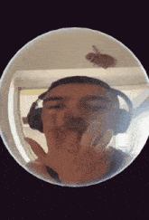 a man wearing headphones is giving the middle finger in a mirror