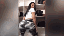 a woman in camouflage pants is dancing in a closet .