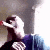 a man is smoking a cigarette in front of a window in a blurry picture .