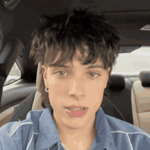 a young man with a mullet is sitting in a car .