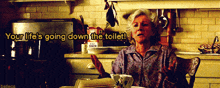 a woman sitting in a kitchen with the words " your life 's going down the toilet "