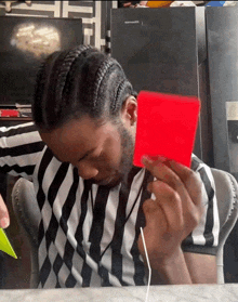 a man in a striped shirt holds a red card