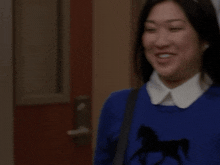a woman in a blue sweater with a black horse on it
