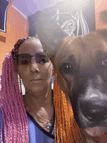 a woman with pink braids is posing for a picture with a brown dog