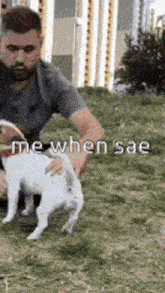 a man is petting a small dog in a park .