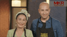 a man and a woman are smiling in front of a mkr ad