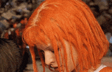 a close up of a woman 's face with bright orange hair