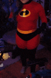a woman in a red sweater is standing in front of a red sign that says the incredibles