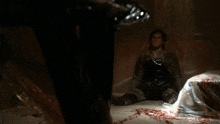 a man is sitting on the floor in a room with blood coming out of the floor