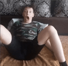 a young boy is sitting on a couch with his legs crossed and making a funny face .