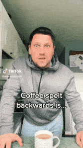 a man is standing in front of a cup of coffee and says coffee spelt backwards