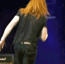 a man with long red hair is standing in front of a marshall amplifier