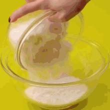 a person is using a red spatula to stir a bowl of food .