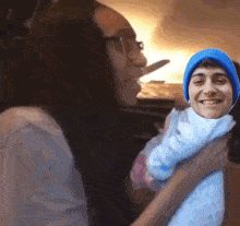 a woman is holding a baby in her arms with a man 's face on the baby .