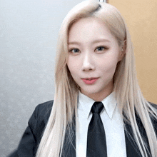 a woman with long blonde hair wearing a black suit and tie