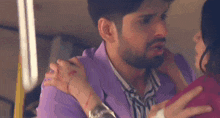 a man in a purple shirt is holding a woman in a pink shirt .