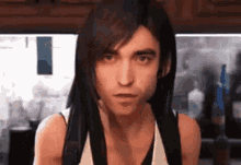 a man with long hair is wearing a white tank top and a backpack .