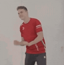 a man in a red shirt is dancing in front of a mirror .