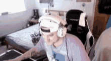 a man wearing headphones and a hat is sitting in a chair in a room .