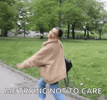 a woman walking in a park with the words " me trying not to care " below her