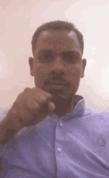 a man in a purple shirt is holding his fist to his mouth