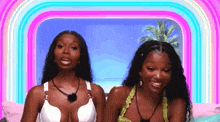 two women in bikinis are sitting next to each other on a bed and smiling .