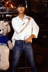 a young man standing next to a teddy bear wearing a blue shirt that says " nice day "