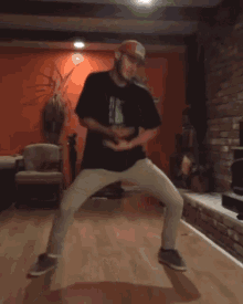 a man is dancing in a living room wearing a black shirt with a frog on it