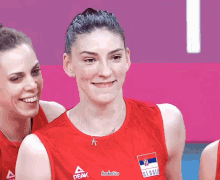 a group of female athletes are posing for a picture with one wearing a red peak jersey
