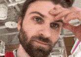 a man with a beard is scratching his forehead .