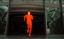 a man in a red bodysuit is walking through a doorway