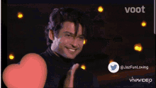 a man in a black shirt is smiling in front of a screen that says voot on it