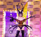 a drag queen in a beetle costume stands in front of a mirror