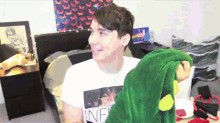 a man wearing a white shirt with the word inf on it is holding a stuffed animal