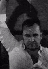 a man in a white shirt is standing with his arms in the air