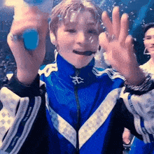 a young boy in a blue jacket is holding a bottle of water in his mouth .
