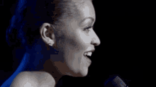 a close up of a woman singing into a microphone in a dark room .