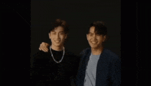 a couple of men are standing next to each other and smiling .