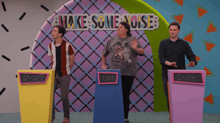 a group of people standing in front of a sign that says make some noise