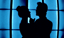 a silhouette of a man and woman dancing in front of a blue background