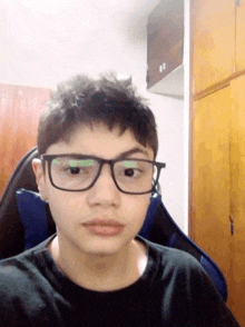 a young man wearing glasses and a black shirt looks at the camera