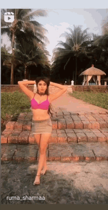 a woman in a bikini is standing on a brick path