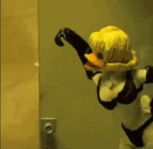 a duck puppet is standing in front of a door wearing gloves and a bra .